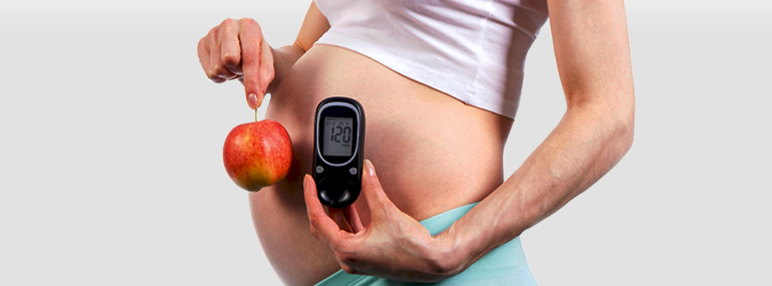 mujer embarazada sostiene una manzana y un glucómetro