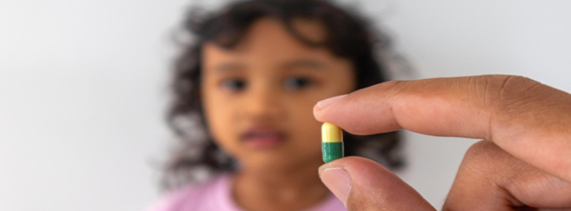 mano sostiene capsula frente a niña